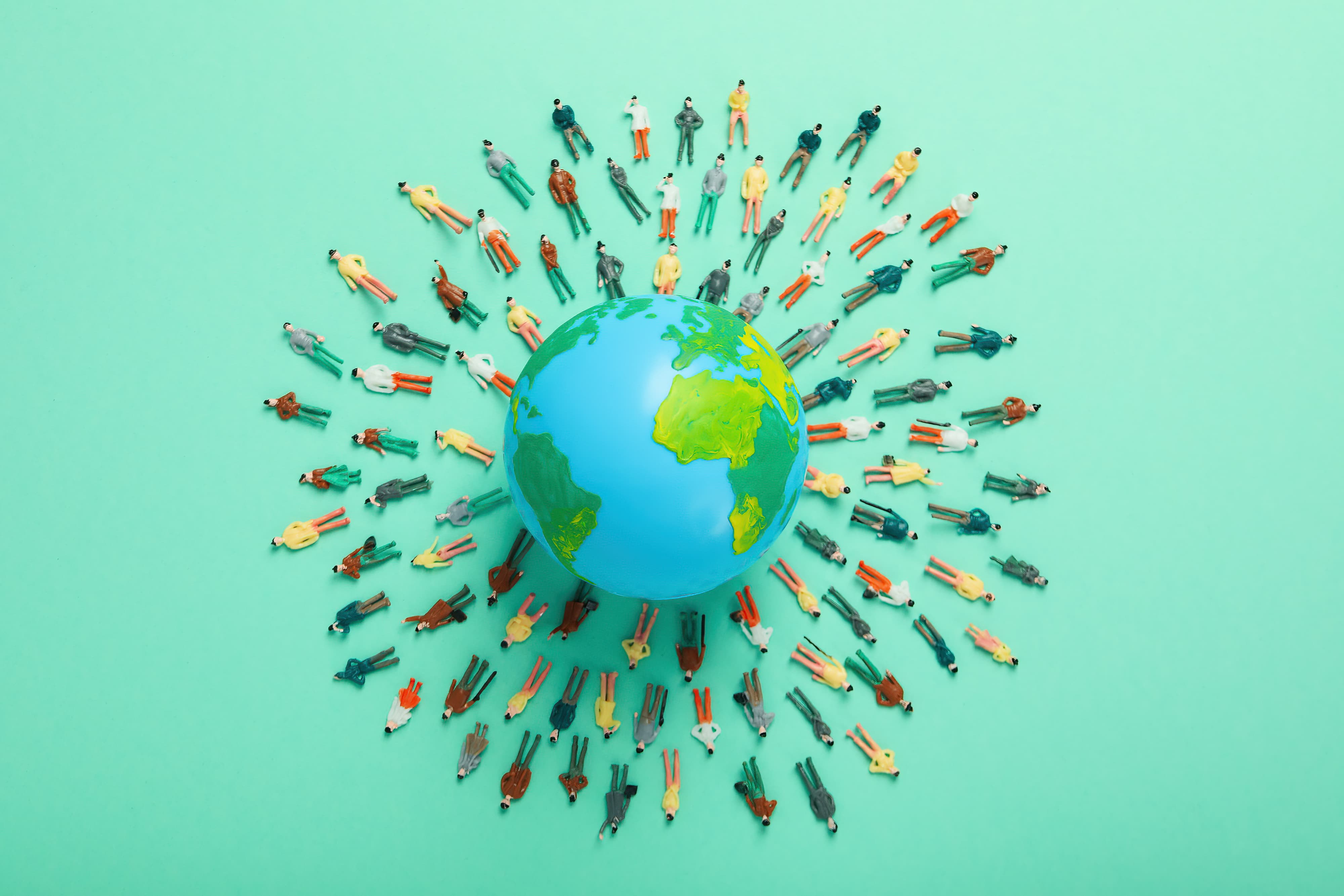 A group of miniature people around a globe